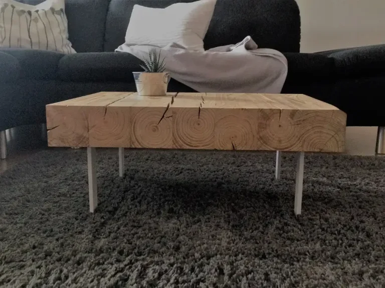 Wo Kraft auf Leichtigkeit trifft: Die markanten Jahresringe der massiven Holzbalken im Detail, getragen von einem minimalistischen Tischbein