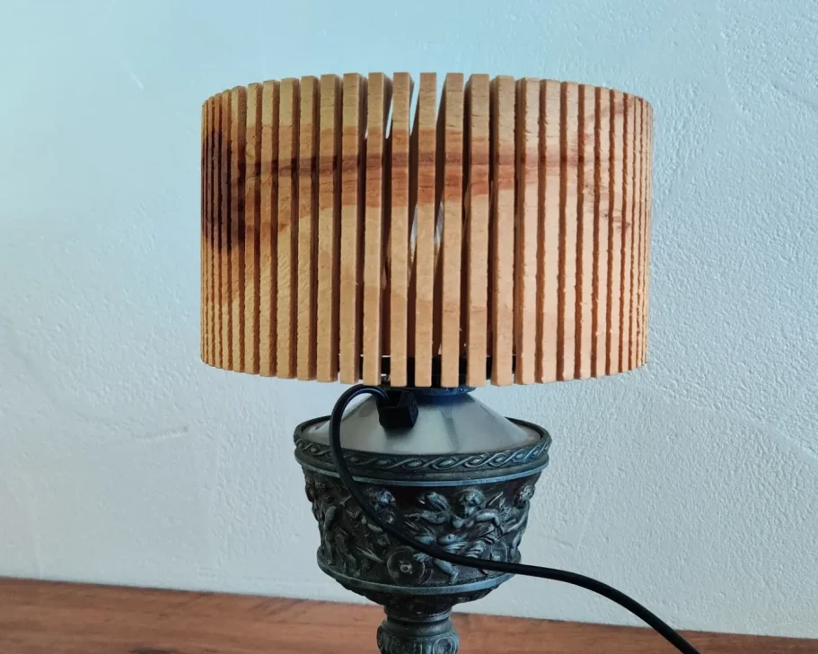 Enzigartige Upcycling-Lampe, die einen modernen Holz-Lampenschirm mit einem kunstvoll verzierten Vintage-Metallfuß vereint.