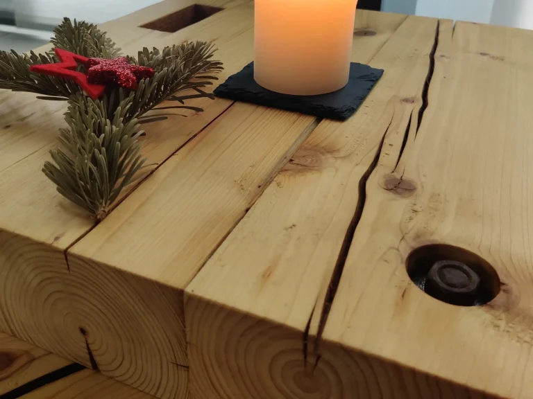 Detailaufnahme der lebendigen Holzmaserung und der natürlichen Risse eines handgefertigten Couchtischs aus alten Dachsparren.